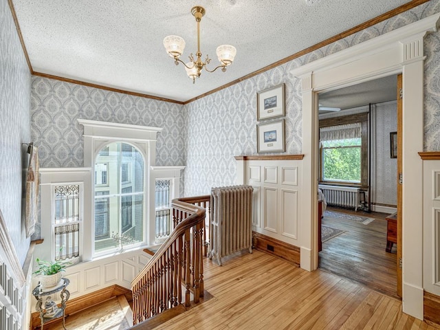 857 Fairmount Ave, Saint Paul, MN 55105 - hall with an upstairs landing, wallpapered walls, ornamental molding, light wood finished floors, and radiator