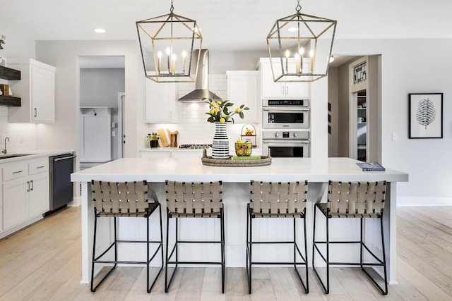 kitchen with a notable chandelier, open shelves, a sink, black dishwasher, and wall chimney exhaust hood