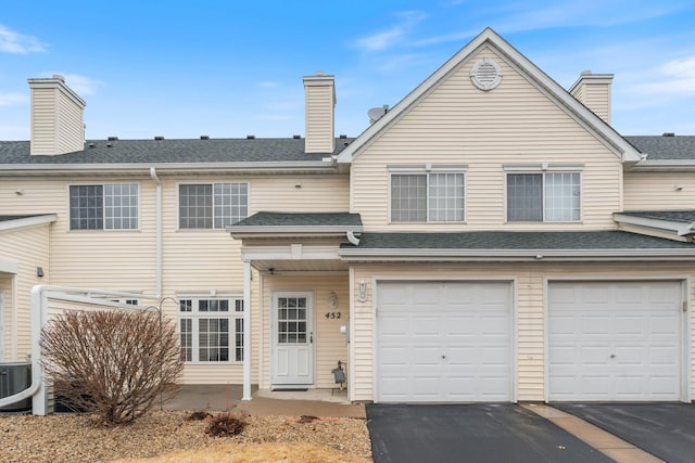 exterior space featuring driveway, a shingled roof, and a chimney