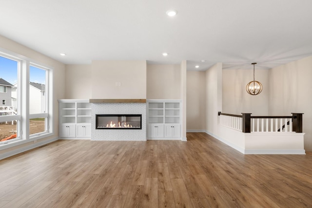 unfurnished living room featuring light wood-type flooring, a tiled fireplace, and recessed lighting