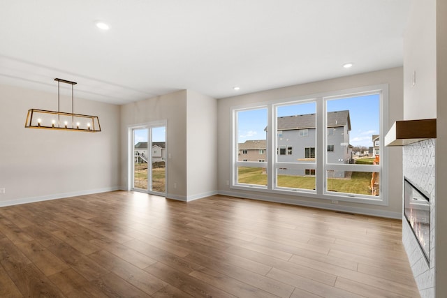 unfurnished living room featuring baseboards, a fireplace, wood finished floors, and a healthy amount of sunlight