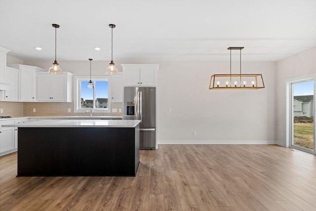 kitchen featuring light countertops, a kitchen island, decorative backsplash, and stainless steel fridge with ice dispenser