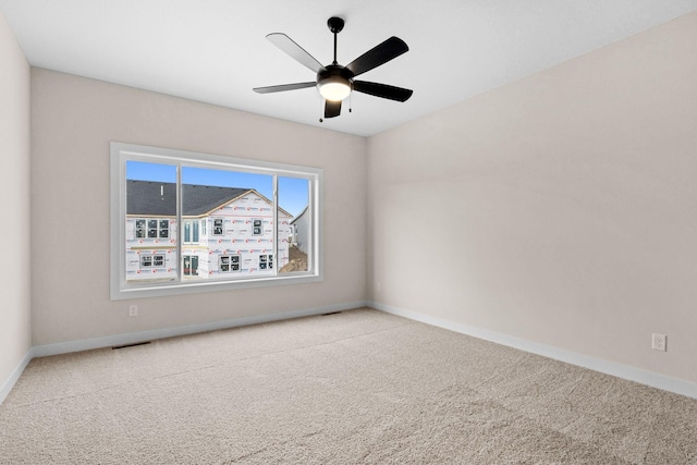 carpeted spare room featuring ceiling fan, visible vents, and baseboards