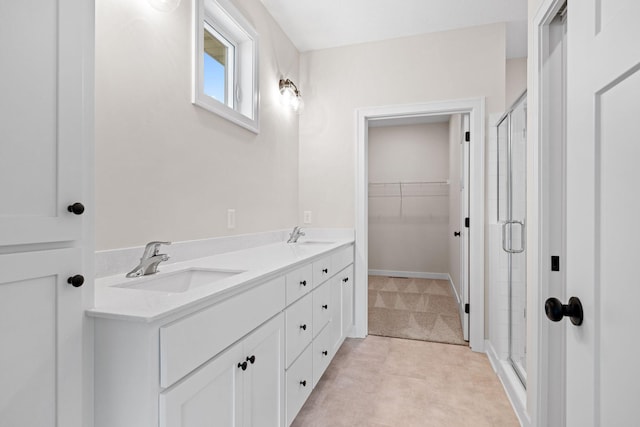 full bath featuring a walk in closet, a sink, a shower stall, and double vanity