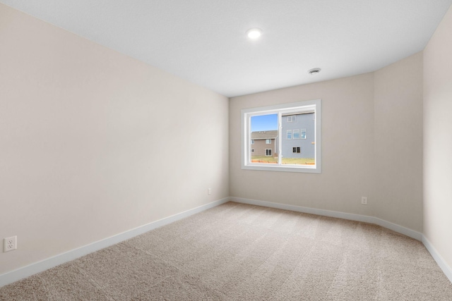 spare room with baseboards and light colored carpet