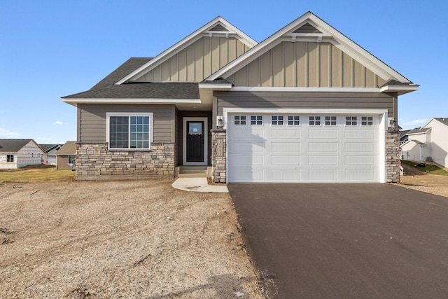 craftsman house with a shingled roof, an attached garage, board and batten siding, stone siding, and driveway