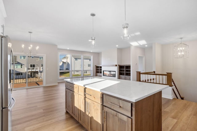 kitchen featuring light wood-style flooring, freestanding refrigerator, open floor plan, a kitchen island, and a multi sided fireplace