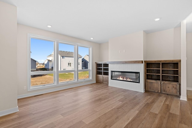 unfurnished living room with recessed lighting, visible vents, a fireplace, and wood finished floors