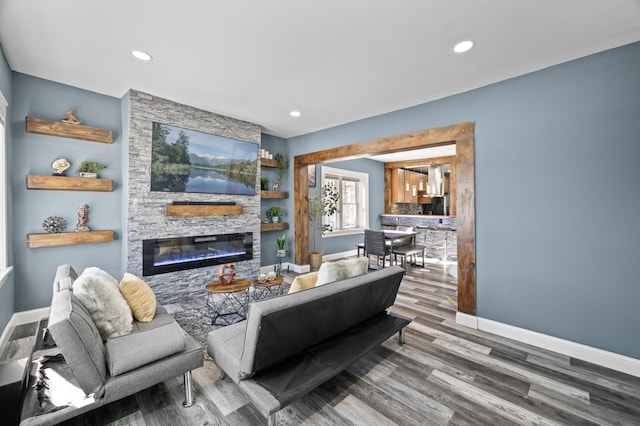 living area featuring a fireplace, baseboards, wood finished floors, and recessed lighting