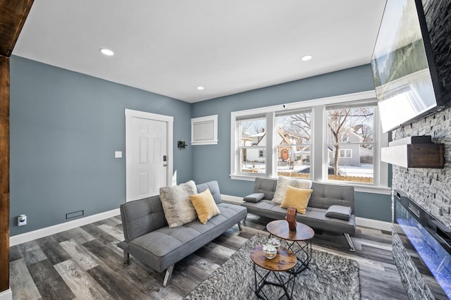 living room featuring recessed lighting, baseboards, wood finished floors, and a stone fireplace