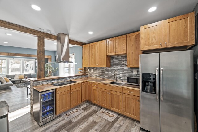 kitchen with beverage cooler, a sink, appliances with stainless steel finishes, backsplash, and island exhaust hood