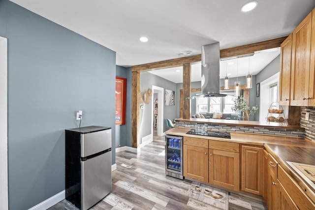 kitchen featuring wine cooler, freestanding refrigerator, island exhaust hood, black electric cooktop, and backsplash