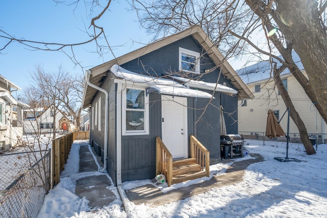 snow covered house featuring entry steps and fence