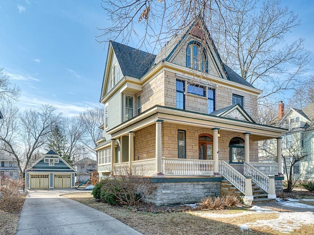 victorian home with a detached garage, an outbuilding, a porch, and roof with shingles