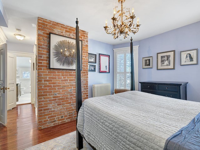 bedroom with a notable chandelier, radiator, brick wall, and hardwood / wood-style floors