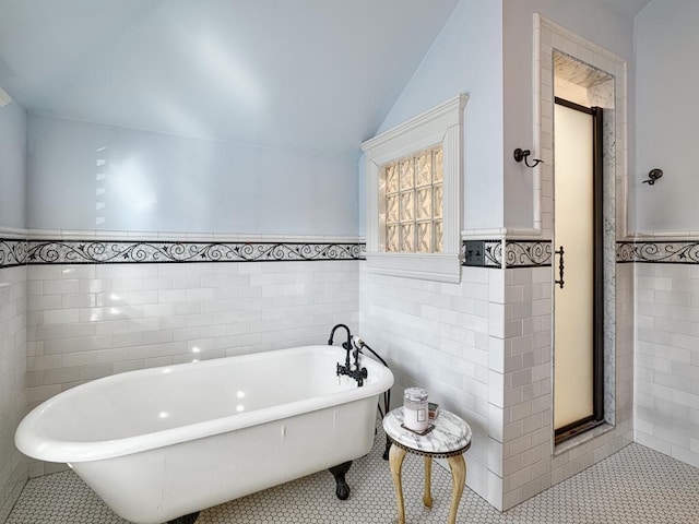 bathroom with tile patterned flooring, vaulted ceiling, and a freestanding tub