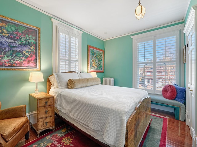 bedroom featuring radiator, wood finished floors, and crown molding