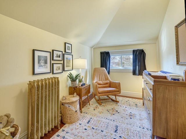 living area featuring lofted ceiling, radiator heating unit, wood finished floors, and baseboards