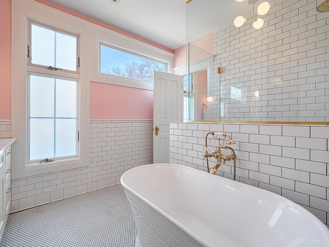 bathroom with a soaking tub, tile walls, a tile shower, and tile patterned flooring