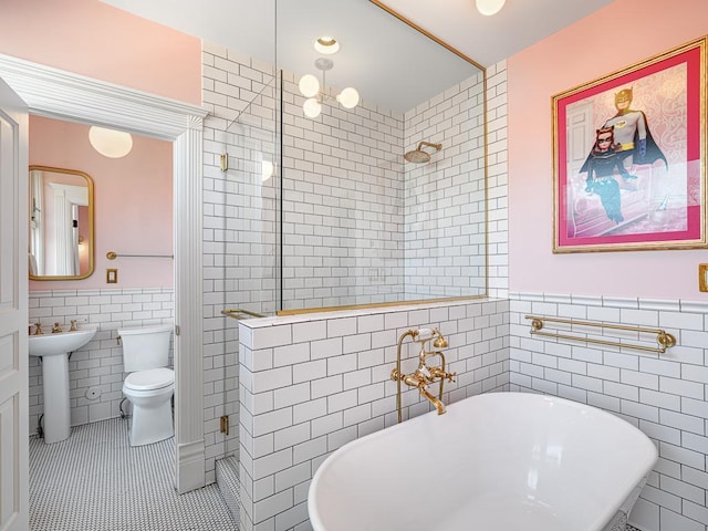 bathroom with a stall shower, a sink, a freestanding bath, tile patterned floors, and tile walls