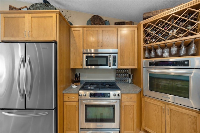 kitchen featuring a textured ceiling, stainless steel appliances, and vaulted ceiling