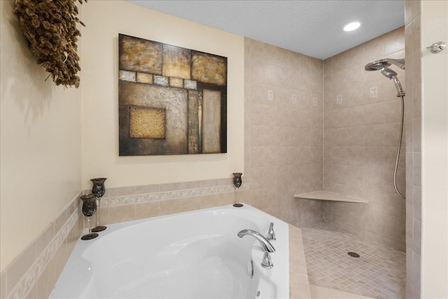 bathroom with a textured ceiling, tiled shower, and a garden tub