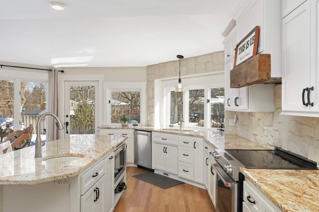 kitchen featuring stainless steel appliances, tasteful backsplash, light wood-type flooring, and a sink