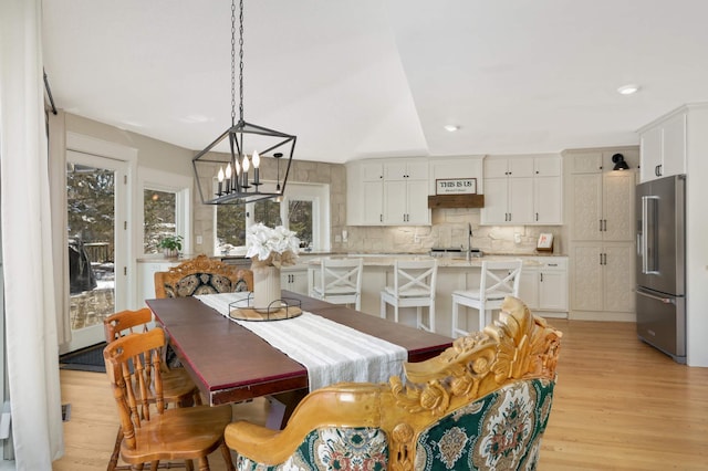 dining space featuring light wood-type flooring, an inviting chandelier, and recessed lighting