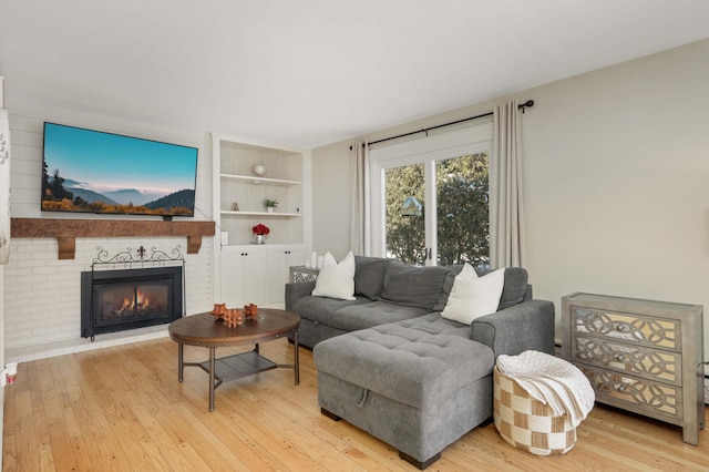 living room with built in shelves, wood-type flooring, and a fireplace