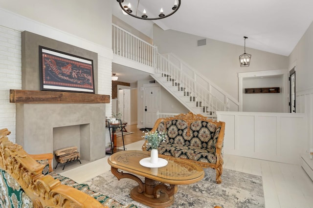 living area with a fireplace, visible vents, stairway, wood finished floors, and a chandelier