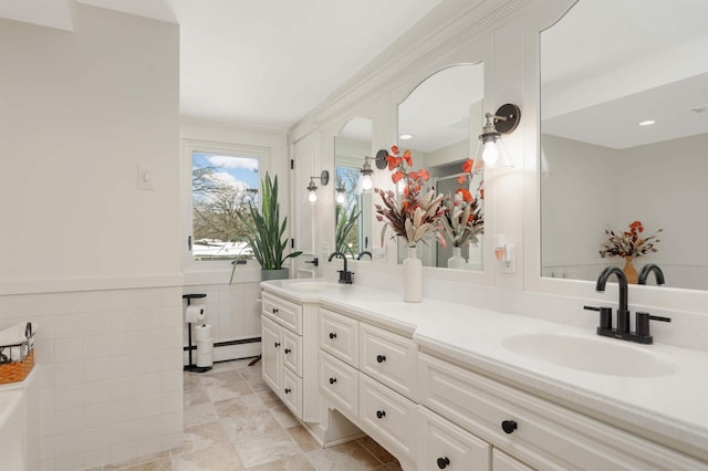 full bathroom featuring a wainscoted wall, double vanity, a sink, and tile walls