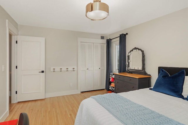 bedroom featuring a closet, visible vents, light wood-style flooring, and baseboards