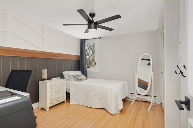 bedroom with a ceiling fan, a closet, light wood finished floors, and baseboard heating