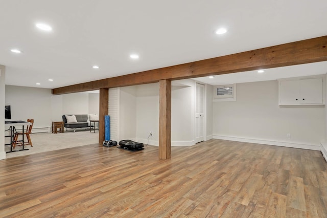 finished below grade area with light wood-type flooring, recessed lighting, baseboards, and a baseboard radiator