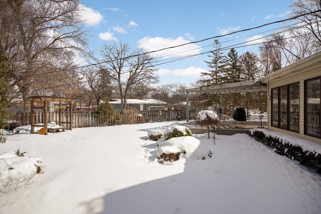 snowy yard featuring fence and a pergola