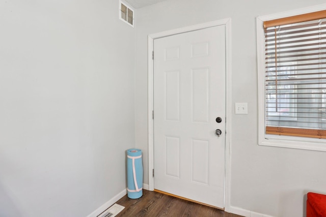 doorway to outside with dark wood finished floors, baseboards, and visible vents