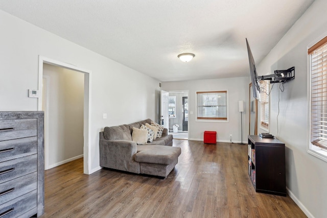 living area featuring a textured ceiling, baseboards, and dark wood-style flooring