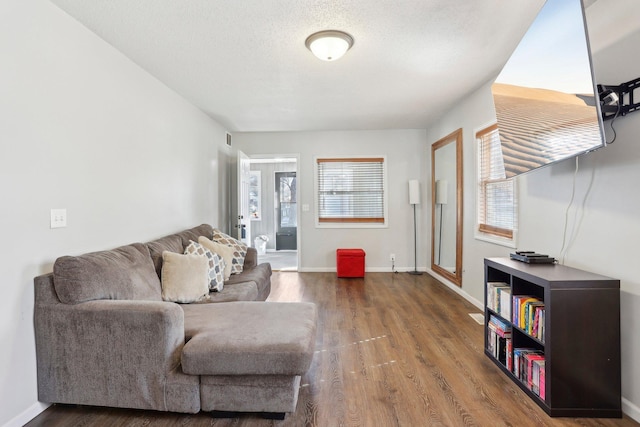 living area featuring visible vents, baseboards, dark wood-style flooring, and a textured ceiling