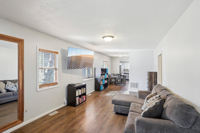 living area featuring visible vents, dark wood-type flooring, and a textured ceiling