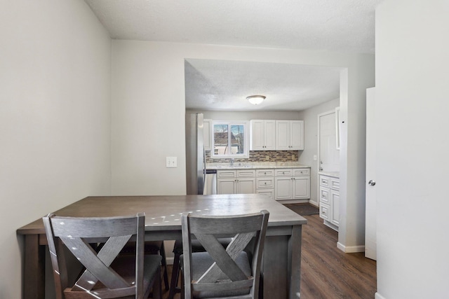 kitchen with backsplash, baseboards, light countertops, dark wood-style floors, and white cabinets