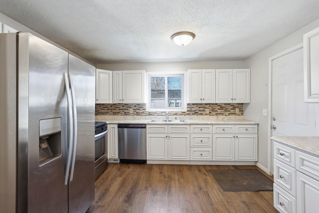 kitchen with a sink, appliances with stainless steel finishes, white cabinetry, and dark wood-style flooring