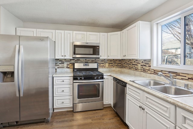 kitchen featuring a sink, appliances with stainless steel finishes, white cabinets, light countertops, and dark wood-style flooring