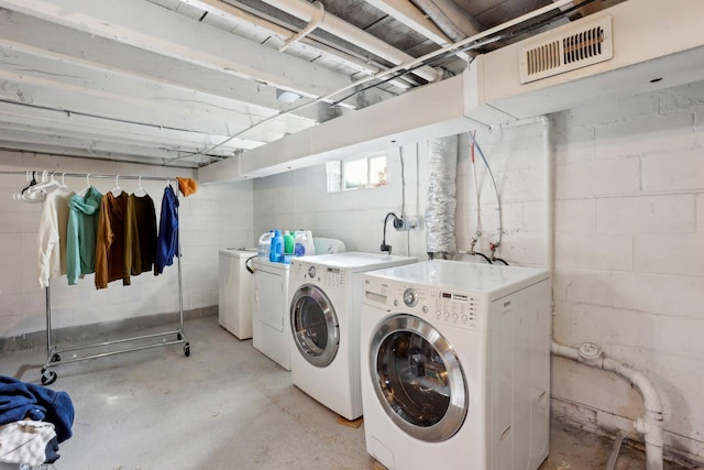 clothes washing area with washer and clothes dryer, laundry area, and visible vents