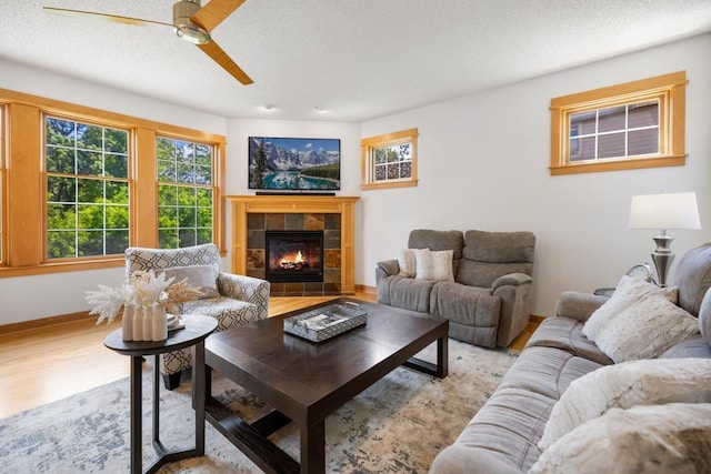 11050 Sweetwater Path, Woodbury, MN 55129 - living area featuring a ceiling fan, a tiled fireplace, wood finished floors, baseboards, and a textured ceiling