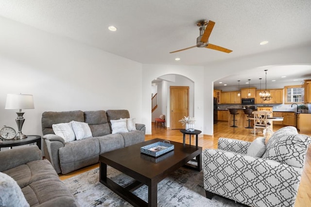 11050 Sweetwater Path, Woodbury, MN 55129 - living area featuring arched walkways, recessed lighting, light wood-style floors, ceiling fan, and stairway