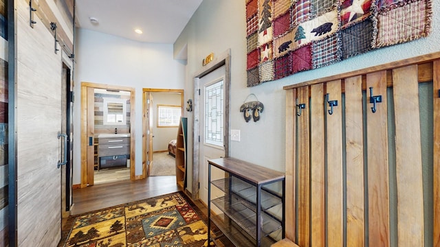 mudroom featuring a sink, a high ceiling, baseboards, and wood finished floors