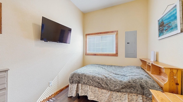 bedroom featuring electric panel, baseboards, and wood finished floors