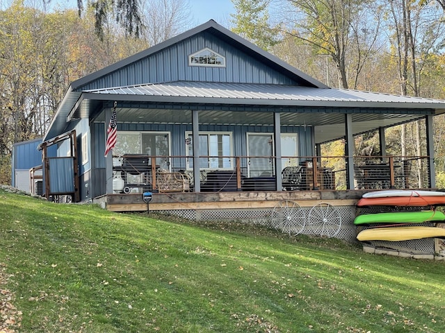 rear view of property with a porch, a yard, board and batten siding, and metal roof