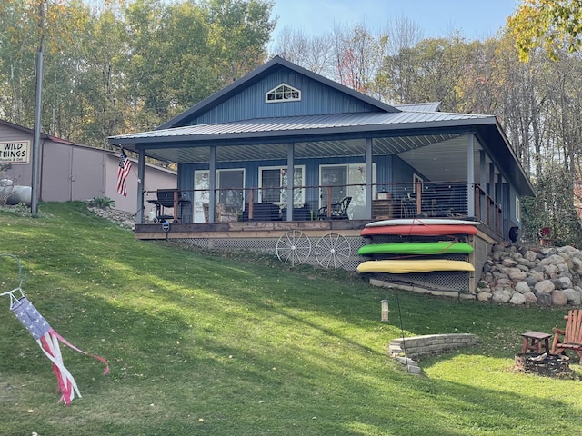 rear view of house with a porch, metal roof, and a yard