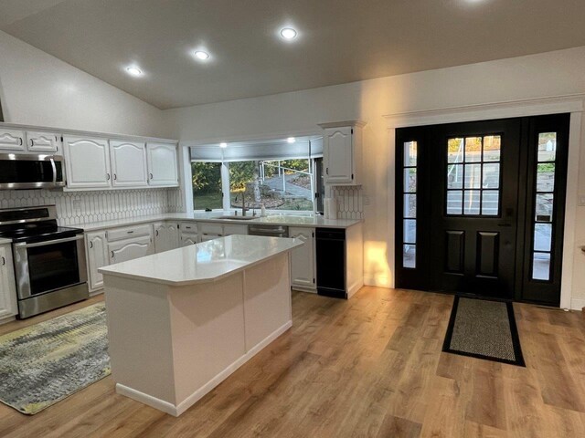 kitchen featuring tasteful backsplash, light countertops, appliances with stainless steel finishes, white cabinets, and light wood-type flooring